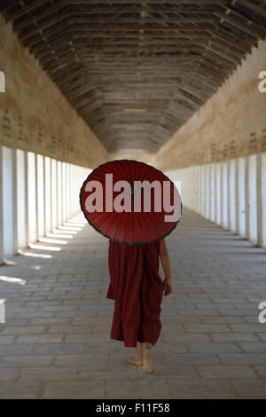 Asian monaco-in-formazione che porta ombrellone in corridoio Foto Stock