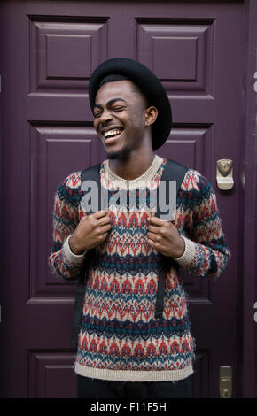 Ridendo uomo nero indossando uno zaino vicino porta viola Foto Stock