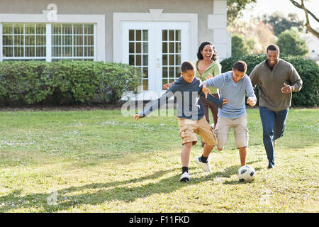 La famiglia che giocano a calcio nel cortile posteriore Foto Stock