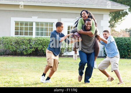 Famiglia giocando a calcio nel cortile posteriore Foto Stock