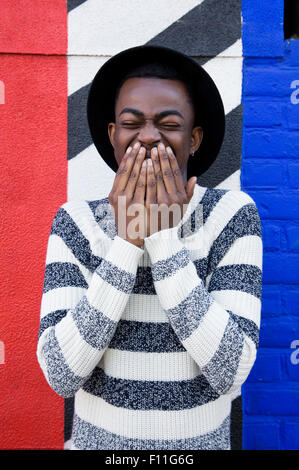 Uomo nero ridere vicino a parete colorata Foto Stock