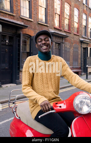 Uomo nero sella scooter su strada urbana Foto Stock