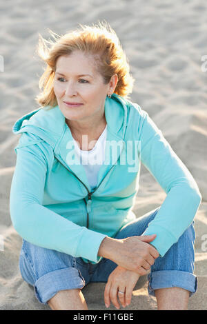 Caucasian donna seduta sulla spiaggia Foto Stock