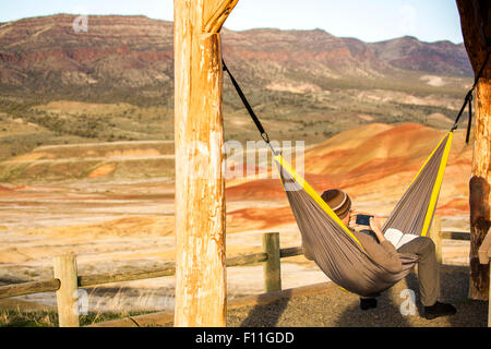 Uomo caucasico di bere il caffè in amaca, colline dipinte, Oregon, Stati Uniti Foto Stock