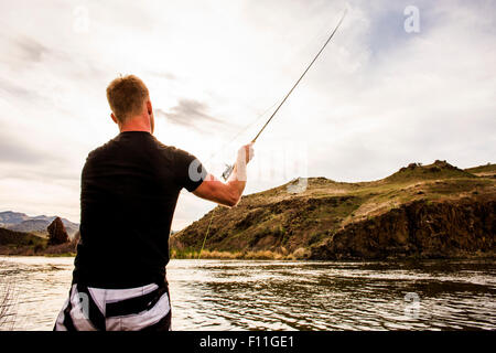 Uomo caucasico pesca nel lago in remoto Foto Stock