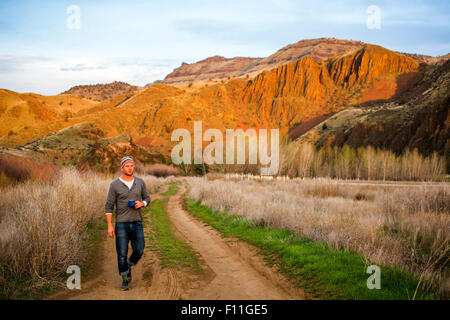 Uomo caucasico di bere il caffè sul tracciato sterrato, colline dipinte, Oregon, Stati Uniti Foto Stock