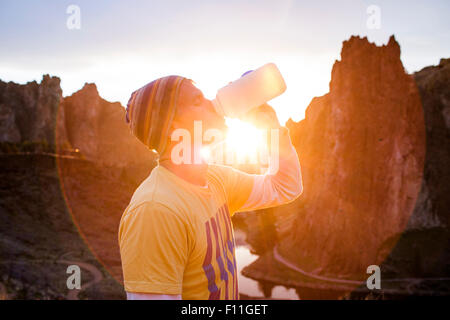 Uomo caucasico di bere acqua in bottiglia il paesaggio del deserto, Smith Rock State Park, Oregon, Stati Uniti Foto Stock