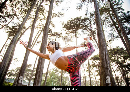 Donna ispanica a praticare yoga in foresta Foto Stock