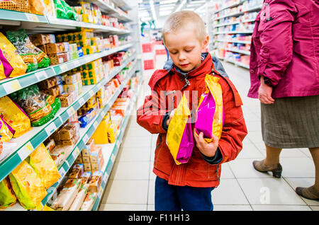 Ragazzo caucasico esaminando borse di cibo nel negozio di alimentari Foto Stock