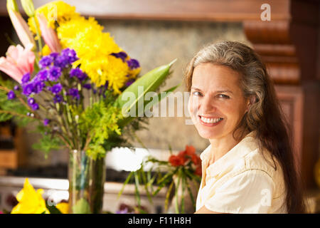 Donna ispanica con fiori in cucina Foto Stock