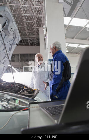 I vecchi meccanismi di origine ispanica a discutere di auto in garage Foto Stock