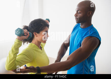 Donna sollevamento pesi con trainer in palestra Foto Stock