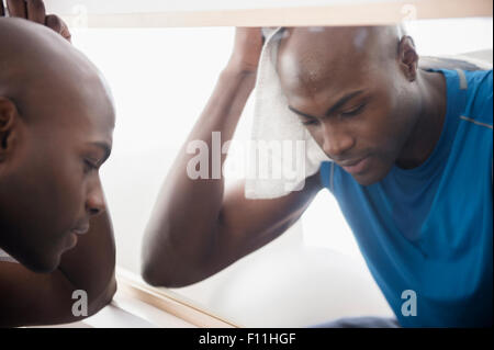 Uomo nero appoggiato vicino a specchio dopo allenamento Foto Stock