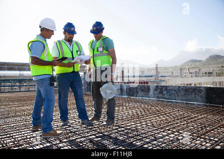 Lavoratori edili parlando sul tondino al sito in costruzione Foto Stock