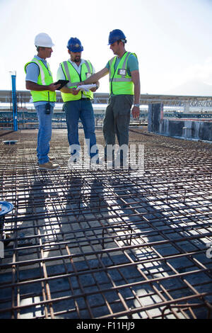 Lavoratori edili parlando sul tondino al sito in costruzione Foto Stock