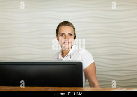 Concierge caucasica sorridente dietro la reception Foto Stock