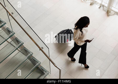 Angolo di alta vista di imprenditrice valigia in hotel lobby Foto Stock