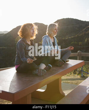 Donne caucasici meditando sulla collina Foto Stock