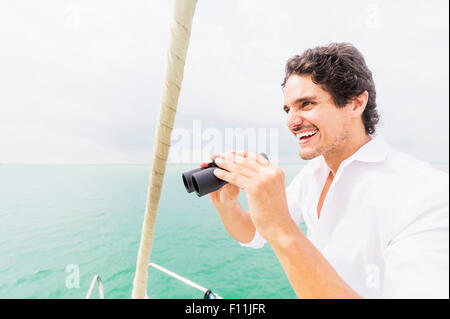 Uomo ispanico guardando fuori dalla barca con il ponte di binocolo Foto Stock