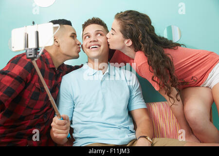 Sorridente amici prendendo selfie baciare le guance dell uomo Foto Stock