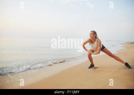 Atleta stiramento sulla spiaggia Foto Stock