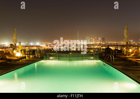 Piscina oltre il paesaggio urbano di notte, Abu Dhabi Emirato, Emirati Arabi Uniti Foto Stock