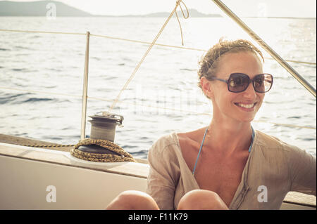 Sorridente Caucasian donna seduta sulla coperta della barca Foto Stock