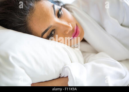 Donna ispanica che stabilisce nel letto Foto Stock