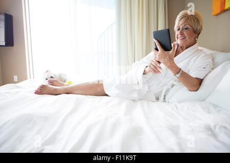 I vecchi donna caucasica utilizzando digitale compressa sul letto Foto Stock