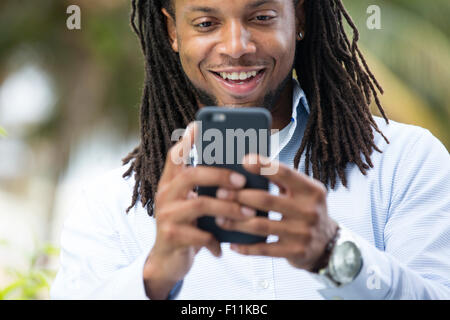 African American businessman tramite telefono cellulare all'aperto Foto Stock