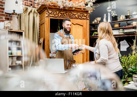 Il dipendente che consentono ai clienti di shopping in negozio Foto Stock