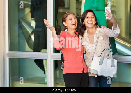 Madre e figlia tenendo selfie al di fuori del negozio Foto Stock
