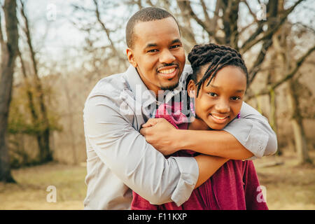 Nero padre e figlia abbracciando all'aperto Foto Stock