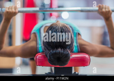 Giovane donna allenamento con barbell sul banco di lavoro in palestra per il fitness Foto Stock