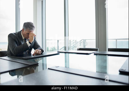 Imprenditore caucasico meditabondo a svuotare tavolo da conferenza Foto Stock