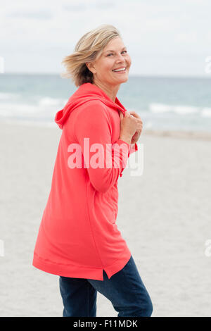 I vecchi donna caucasica camminando sulla spiaggia Foto Stock