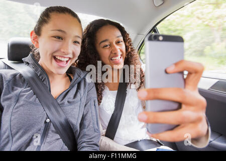 Le ragazze adolescenti tramite telefono cellulare in auto sedile posteriore Foto Stock