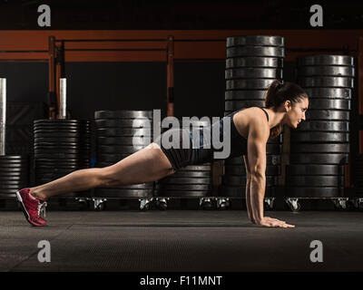 Atleta caucasica facendo push-up in palestra Foto Stock