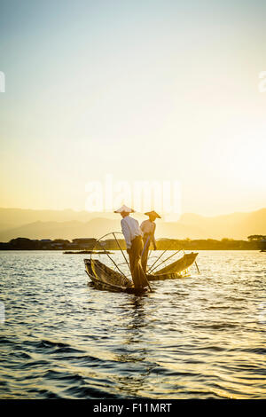 Asian pescatori pesca in canoa sul fiume Foto Stock