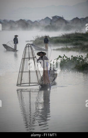 Asian pescatori pesca in canoa sul fiume Foto Stock