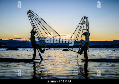 Asian pescatori che utilizzano le reti da pesca in canoa sul fiume Foto Stock