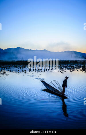 Asian pescatore con rete da pesca in canoa sul fiume Foto Stock