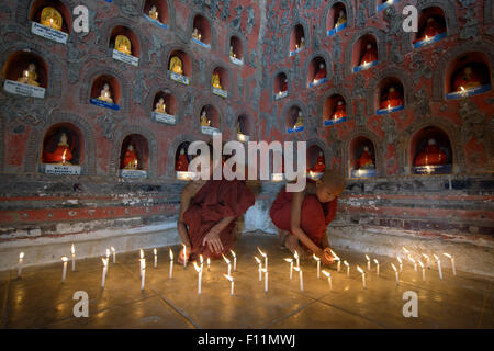 Asian monaci-in-formazione accendendo candele in antico tempio Foto Stock