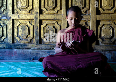 Asian monaco-in-formazione utilizzando il cellulare in tempio Foto Stock