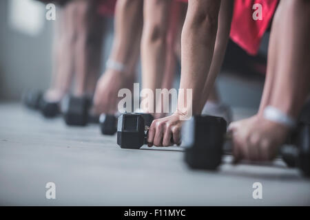 Gli atleti facendo push-up e il sollevamento dei pesi sul pavimento Foto Stock