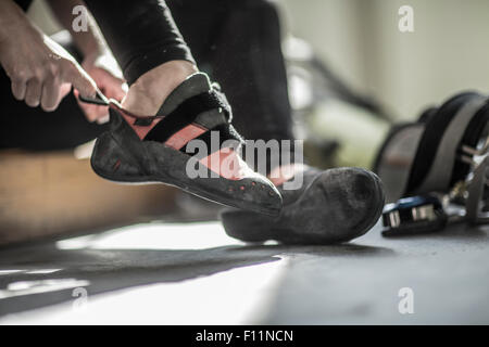 Atleta tirando su scarpe da arrampicata in palestra Foto Stock