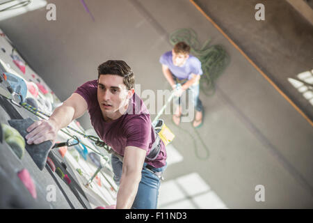 Angolo di alta vista di atleta arrampicata su parete di roccia in palestra Foto Stock
