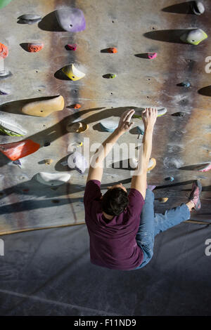 Angolo di alta vista di atleta arrampicata su parete di roccia in palestra Foto Stock