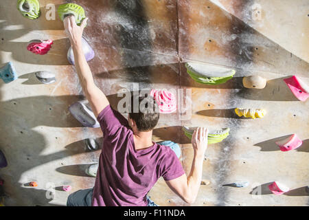 Angolo di alta vista di atleta arrampicata su parete di roccia in palestra Foto Stock