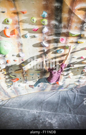 Angolo di alta vista di atleta arrampicata su parete di roccia in palestra Foto Stock